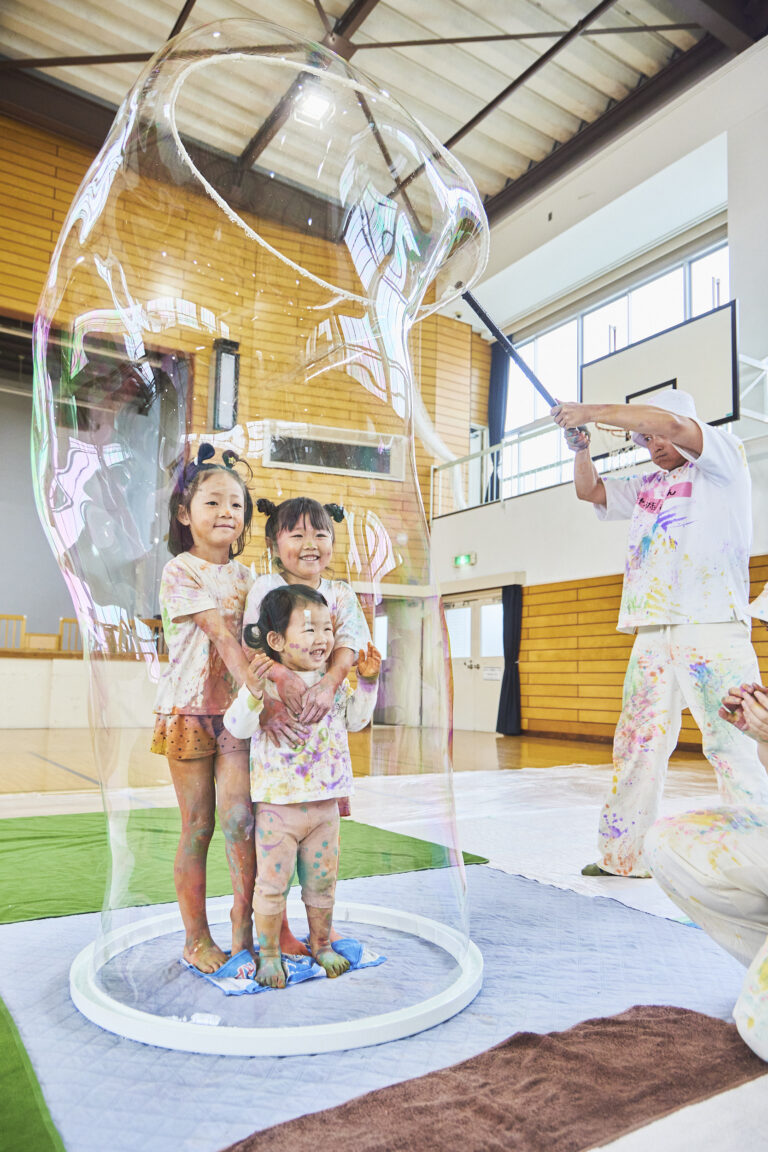 体育館で大きなシャボン玉の中に入って驚く園児たち