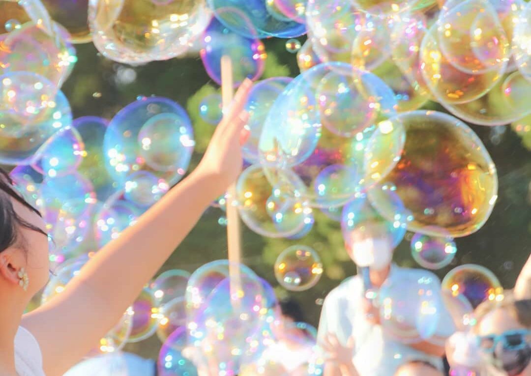 目の前に広がる虹色のシャボン玉に手をのばす子ども