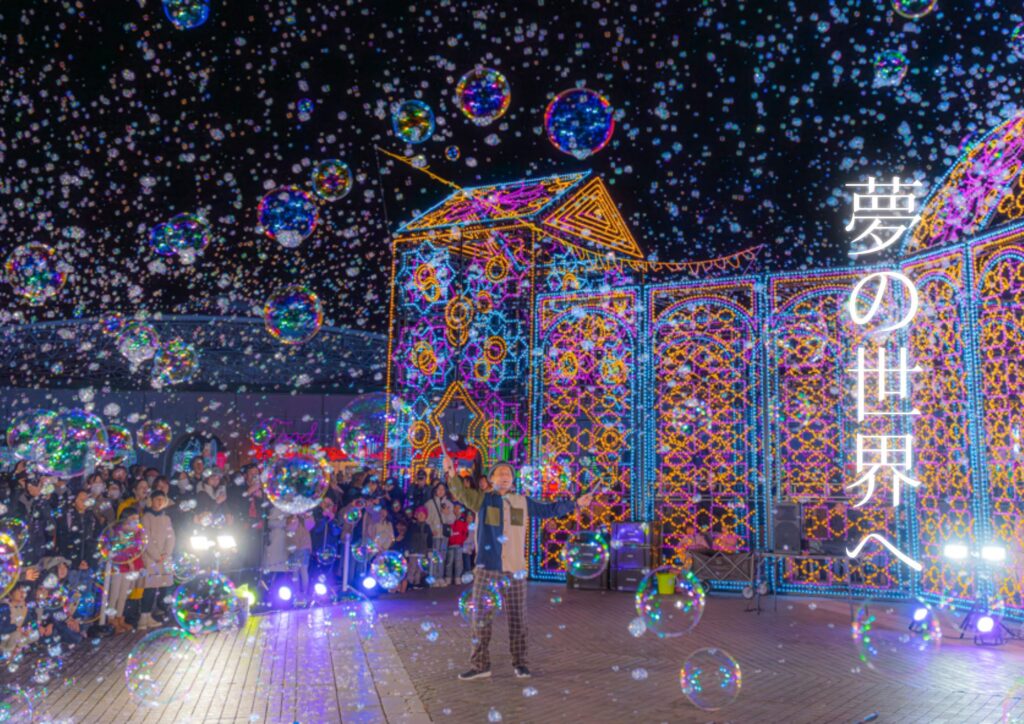 神戸イルミナージュのイルミネーションの前で、照明に照らされたシャボン玉が夜空に舞うナイトバブルショー