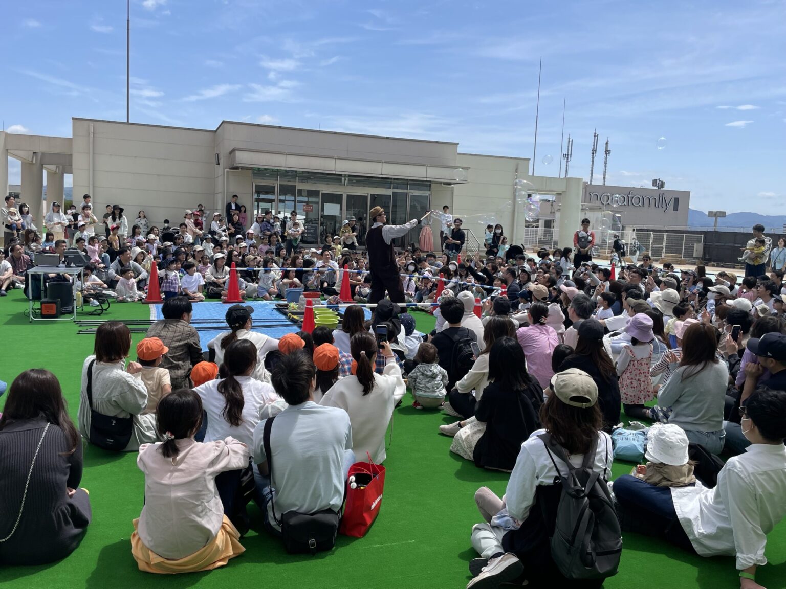 ならファミリー屋上広場で開催したお昼のシャボン玉ショー。青空の下、約300人の家族連れが芝生に座って見ている