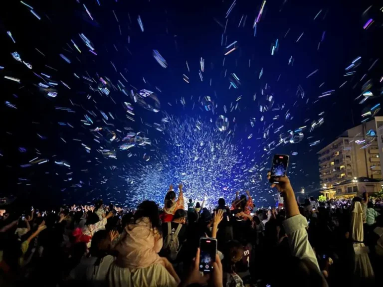 Audience on Kaike Onsen beach watching bubbles glow in blue light, Tottori