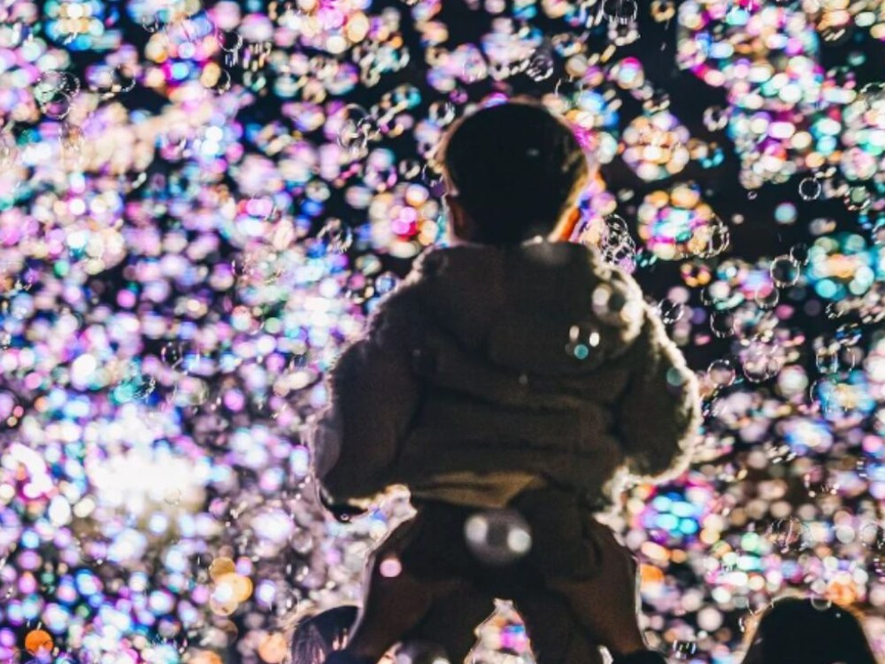 Children and adults looking up at bubbles together