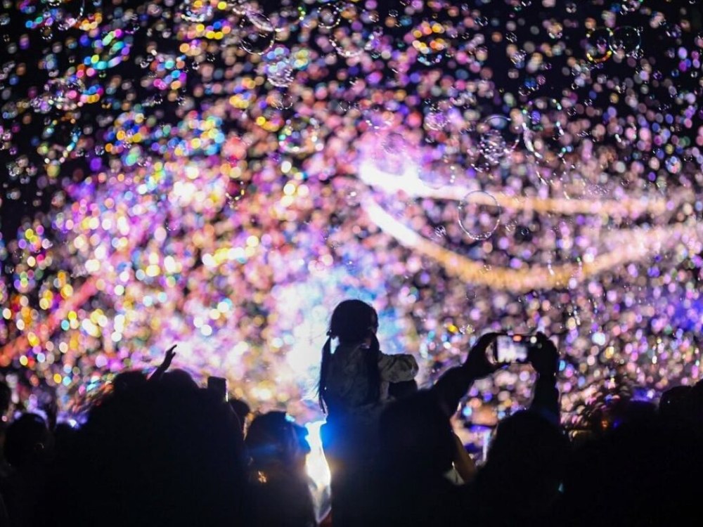 Visitors surrounded by glowing bubbles at a night bubble show