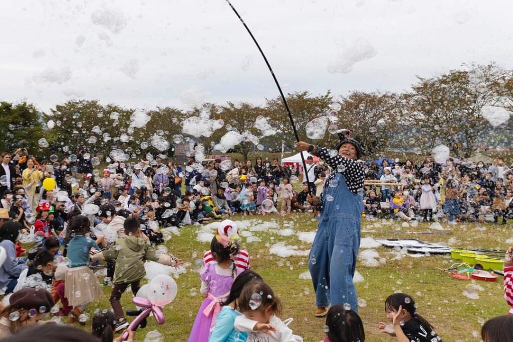公園の芝生で行われた出張シャボン玉ショー。空いっぱいのシャボン玉に、たくさんの家族連れと子どもたちが手をのばしている