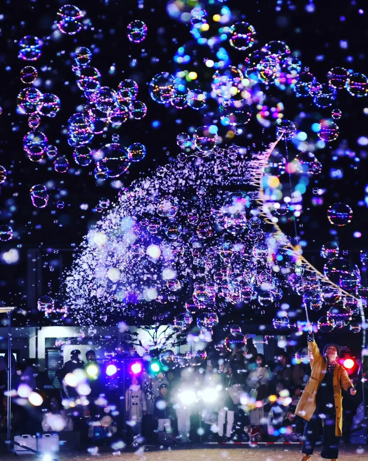 紫の光に照らされて夜空に舞う無数のシャボン玉